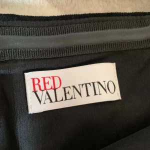Svart axelbandslös klänning Red Valentino - Säljer en svart axelbandslös kortklänning från Red Valentino. Överdelen är i mjuk sammet och kjolen har en lätt utsvängd form i slätt tyg. Perfekt för dig som gillar stilrena och eleganta plagg med lyxig känsla.