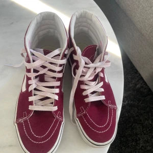 Vinröda Vans sneakers  - Säljer ett par klassiska Vans Sk8-Hi sneakers i vinrött mockatyg med vita detaljer och snörning. Skorna har hög modell, vit sula och den ikoniska sidoremsan. Pris kan diskuteras💕