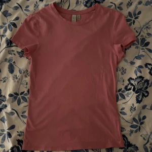 Rosa t-shirt från & Other Stories XS - Snygg rosa t-shirt från & Other Stories i storlek XS. Modellen är klassisk med rund hals och korta ärmar. T-shirten är gjord i mjuk bomull och har en clean look utan mönster eller detaljer. Perfekt för dig som gillar enkel och stilren vibe.