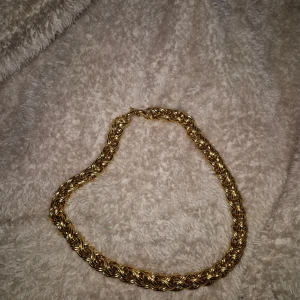 Guldigt halsband från Monet - Säljer ett chunky halsband från Monet i guldtonad metall. Kedjan har ett flätat, tvinnat mönster som ger en lyxig och cool vibe. Perfekt för dig som vill sticka ut med ett statement piece. Lås med tydlig Monet-gravyr.