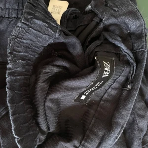 Mörkblå linnebyxor från Zara - Snygga mörkblå linnebyxor från Zara med elastisk midja bak och klassisk knapp framtill. Byxorna har raka ben och passar till någon som är ca 185 cm. Säljes endast då de är för små åt min pojkväns lillebror❣️❣️ 