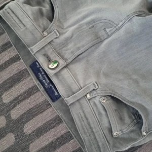 Grå jeans från Jacob Cohen, stl 26 - Snygga grå jeans från Jacob Cohen i klassisk femficksmodell. Jeansen har raka ben, silverfärgade detaljer och en broderad etikett bak. Tillverkade i mjuk bomullsblandning med diskret tvättad look och fina sömmar. Perfekta för en stilren och avslappnad outfit.