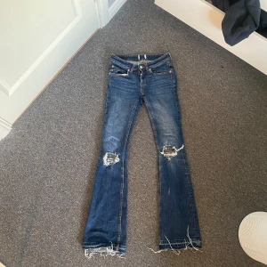 Blå bootcut jeans med slitna knän - Lågmidjade jeans, en liten fläck på vänster ben därav priset, har dock inte testat att få bort💗