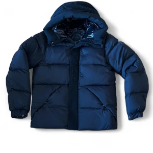  Moncler dunjacka med huva - Säljer en mörkblå dunjacka från Moncler med stor huva och klassisk logga på ärmen. Jackan är puffer-modell med breda kanaler, elastiska muddar och blanka detaljer på insidan. Perfekt för kalla dagar och riktigt snygg till streetwear.