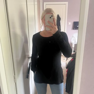 Svart ribbad stickad tröja - Säljer en svart, ribbad stickad tröja med lång ärm och rund hals.. Enkel och stilren design som funkar till det mesta. Har slits på båda sidor. Knappt använd. Fråga gärna vid funderingar.😊passar även M