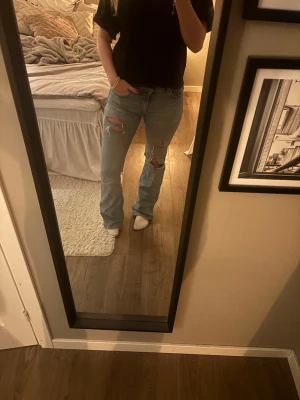 Ljusblå slitna jeans - ljusblå jeans med  flera slitningar på knäna och låren. De är i denim och har en avslappnad passform som ger en cool vibe. De är hål mellan benen som ni ser på bilden