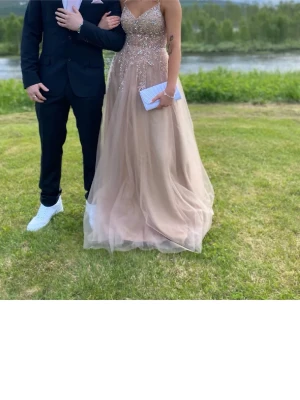 Ljus rosa långklänning - Säljer en magisk långklänning i ljus champagne/ rosa färg med glittrig överdel och tunna axelband. Kjolen är i flera lager tyll som ger ett drömmigt fall. Perfekt till bal eller student. Köpte klänningen här på Plick men den var lite kort på mig så säljer vidare