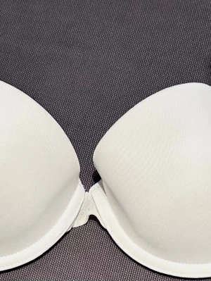 Vit BH från H&M, 75B - En enkel och stilren vit BH från H&M i storlek 75B. BH:n har släta kupor och justerbara axelband för bästa passform. Tillverkad i mjukt och bekvämt material som känns skönt mot huden. Perfekt under alla typer av toppar.