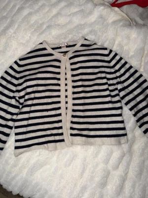 Randig kofta i marinblå och vit - Säljer en mysig randig kofta i marinblått och vitt. Koftan har en enkel knapp framtill, rund halsringning och långa ärmar. Perfekt att slänga över en t-shirt för en chill look. Materialet känns mjukt och stickat. passar även xxs-xs, eventuellt S