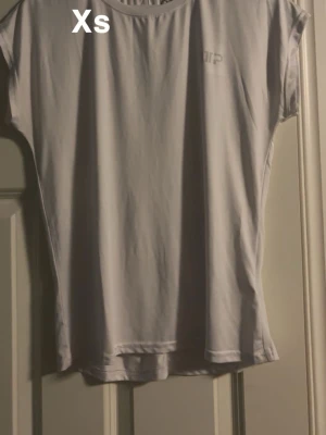 Vit kortärmad t-shirt från MP - En basic vit t-shirt från MP i storlek XS. T-shirten har korta ärmar och en relaxed passform, perfekt till alla tillfällen. Tillverkad i mjukt material som känns skönt mot huden. Enkel och stilren design med liten logga på bröstet.