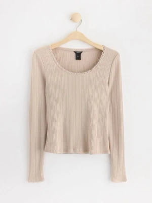 Beige ribbad topp från Lindex - Säljer en beige långärmad topp från Lindex i ribbad bomullsmix. Toppen har rund halsringning med söt spetsdetalj och smal passform. Perfekt att styla med jeans eller kjol för en enkel men snygg look.
