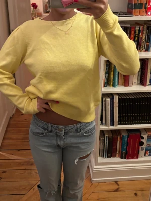 Ljusgul stickad tröja - En ljusgul stickad tröja med rund hals och ribbade muddar. 