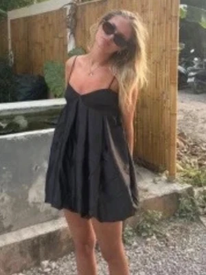 Svart kort klänning med tunna axelband - Supersöt svart kort klänning med tunna axelband och vidd i kjolen. Perfekt för varma dagar och enkel att styla med sneakers eller sandaler. Lätt och luftig modell som ger en avslappnad men ändå chic vibe.