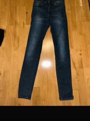 Blå shaping skinny jeans från H&M - Säljer ett par blå shaping skinny jeans från H&M med regular waist. Klassisk femficksmodell, dragkedja och knapp framtill. Jeansen har en snygg tvättad look och sitter tight hela vägen ner.