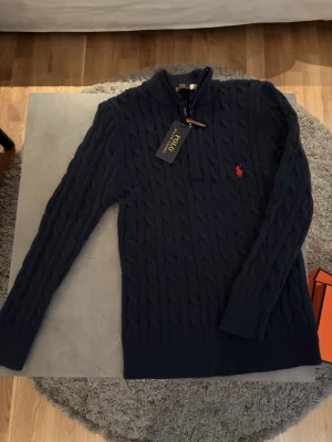 Marinblå stickad half zip från Polo Ralph Lauren - Säljer en marinblå half zip från Polo Ralph Lauren med stretchigt material och väldigt bra passform, passar bäst för dig om är mellan 160-175cm.