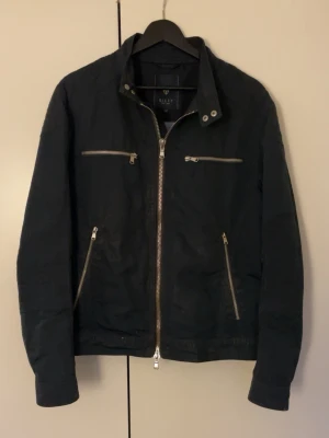 Mörkblå jacka från Riley - Säljer en riktigt fin mörkblå jacka från Riley. Den är i fint skick och perfekt till höst och vår. Jackan är i storlek 48, vilket är i kostymstorlek men motsvarar ungefär S/M. Priset är ej hugget i sten och om du har frågor är det bara att skriva.