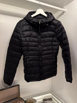 Svart pufferjacka - ONLY - Säljer en svart pufferjacka från ONLY i storlek M. Jackan har huva, dragkedja framtill och quiltad design. Jackan är använd fåtal gånger och är i mycket fint skick. Bär oftast storleken S men i just denna modell var det mer passande med M, hör av dig om du vill se hur den sitter på! 