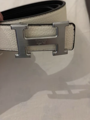 Vitt bälte - Vitt bälte med silvrig logga i längden 105