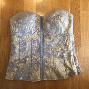 Guldkorsett - Säljer en snygg axelbandslös korsett med glittrigt guldfärgat blommönster. 