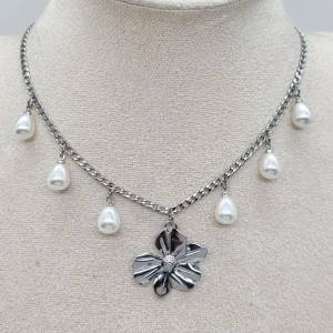 Stilfullt halsband  - Stilfull halskedja med blomma och pärlor.           Material: rostfrit stål                                                                   Längd: 40-45 cm. Kedjetjocklek-3mm. .Nickelfri Priset utan ask blir lägre.