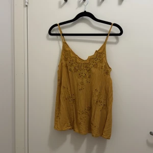 Gul broderad linnetopp från Lindex - Säljer en gul linnetopp från Lindex i storlek S. Toppen har tunna axelband, v-ringning och vackra broderade detaljer framtill. Materialet är lätt och luftigt, perfekt för varma dagar. Snyggt avslappnad passform och fina broderier som ger en bohemisk känsla.