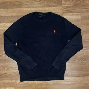 Mörkblå tröja från Polo Ralph Lauren XS - Mörkblå långärmad tröja från Polo Ralph Lauren i mjuk pima bomull. Klassisk rund hals och röd broderad logga på bröstet. Perfekt för dig som gillar stilrena och tidlösa plagg med en snygg detalj.