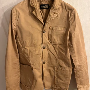 Beige kavajjacka från Wacay - Snygg beige kavajjacka från Wacay med tre stora fickor framtill och klassisk krage. Jackan har knäppning med tre knappar och är tillverkad i mjuk bomull. Funkar att klä upp eller klä ner. 