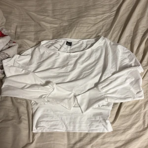 Vit långärmad topp från Gina Tricot - Vit långärmad topp från Gina Tricot i storlek M. Toppen har bred resår i midjan och lätt puffade ärmar med smalare muddar. Materialet är mjukt och stretchigt, perfekt för en clean och fräsch look. Rund halsringning och enkel design. Går off-shoulders, aldrig använt!