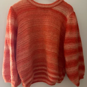Randig orange stickad tröja Lindex - Säljer en mysig stickad tröja från Lindex i storlek L. Tröjan har ett randigt mönster i olika nyanser av orange och ljusbeige, med ribbad hals och långa ärmar. Perfekt för dig som gillar färg och vill ha en chill vibe på hösten eller vintern.