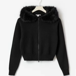 Svart stickad hoodie med fakepäls - Svart stickad hoodie med dragkedja och huva kantad med mjuk fakepäls. Tröjan har ribbade muddar vid ärmslut och nederkant, samt lång ärm. Perfekt för dig som gillar en chill och snygg look med lite extra edge.