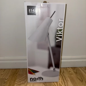 Viktor Skrivbordslampa - Modern skrivbordslampa i vitt med justerbar skärm och arm. 1,6 m sladd med strömbrytare. Passar E14-lampa, max 40W (ingår ej). Lampan och förpackningen är i mycket fint skick, inga synliga defekter eller slitage.