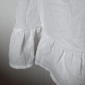 Vit linnetopp med volang  - Säljer en vit linnetopp från Cubus i storlek XS. Toppen har smala axelband, v-ringad hals och snygga volangdetaljer nedtill och vid ärmslut. SKRIV INNAN KÖP!