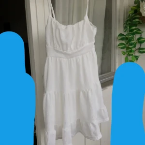 Vit somrig kortklänning  - Supersöt vit kortklänning med tunna axelband som går att justera och smockad överdel. Klänningen har volangig kjol. Den är S men passar M oxå