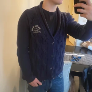 Vintage blå stickad cardigan - Väldigt fin vintage stickad Tommy Hilfiger cardigan. Passar bra nu till kallare väder. Modellen är 180cm, 73kg. Priset går att diskutera så tveka inte på att skicka iväg ett prisförslag!