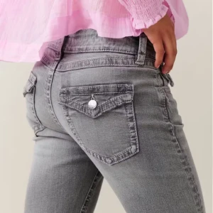 Grå bootcut jeans med fickdetaljer - Snygga grå jeans med bootcut passform och coola fickor med lock och knapp bak. Jeansen har låg midja och är tillverkade i stretchigt denim för en bekväm känsla. Perfekta för dig som gillar en avslappnad men trendig stil.
