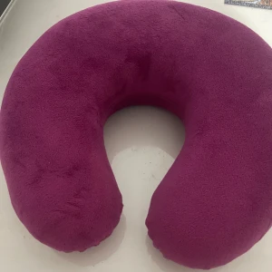 Nackkudde - Rosa nackkudde i mjukt tyg, perfekt för resor eller avkoppling. Kudden ser ut att vara i gott skick utan synliga fläckar eller skador. Ergonomisk design för extra komfort under längre sittande perioder.