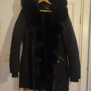 Svart pälsjacka med fluffig krage - Säljer en svart vinterjacka med avtagbar päls på jackan samt armar. Pälsen är extra fluffig och bred krage samt pälsdetaljer längs hela framsidan och ärmsluten. Jackan har dragkedja och fickor med snygga detaljer. Perfekt för dig som vill ha en snygg jacka till vintern. Använd 2 gånger. Nypriset var 1999 kr säljes nu för 1000 kr. Står XL i men är e EU storlek så är som en L