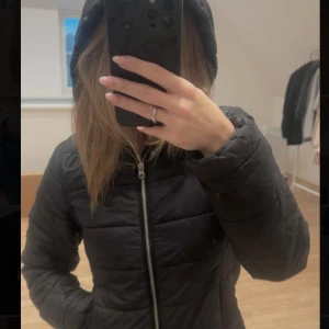 Svart quiltad pufferjacka med huva - Säljer en svart pufferjacka med huva och quiltad design. Jackan har en rak passform, långa ärmar och  fickor på sidorna. Perfekt för kyliga dagar❤️