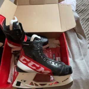 CCM JetSpeed hockeyskridskor svart/röd - Säljer ett par grymma CCM JetSpeed hockeyskridskor i svart och rött med vit sula. Skridksorna e helt nya aldrig använda inte ens värmda. Skridskorna har en sportig design med robust snörning och extra stöd runt ankeln. Yttermaterialet är syntet och insidan har mjuk vaddering för komfort. Perfekt för dig som vill ha fart på isen.