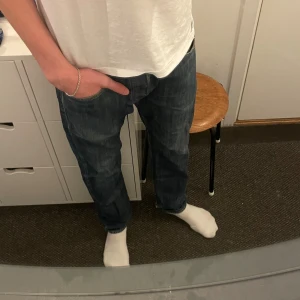 Levi's 501 mörkblå jeans straight fit - Klassiska Levi's 501 jeans i mörkblå tvätt med raka ben och normal passform. Jeansen har fem fickor, knappgylf och den ikoniska läderpatchen bak i midjan. Perfekta för en avslappnad och tidlös look.