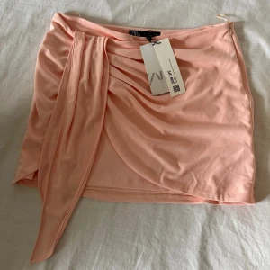 Ljusrosa omlottkjol från Zara - Snygg ljusrosa kortkjol från Zara med omlottdetalj och drapering framtill. Helt oanvänd 💕