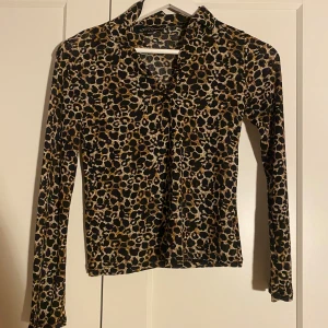 Leopardmönstrad långärmad blus  - Säljer en snygg långärmad blus/topp från XOXO friends med leopardmönster i svart, beige och bruna toner. Toppen har en mjuk och stretchig känsla, med en liten krage och figurnära passform. Passar mig som i vanliga fall har stl S