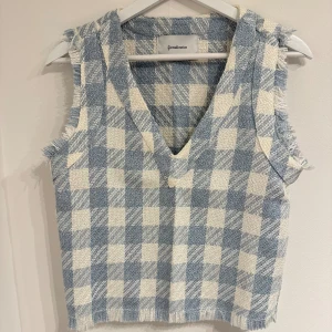 Blåvit rutig väst från Stradivarius - New, no sign of use. Snygg väst från Stradivarius i blåvitt rutigt mönster. Västen har en v-ringad hals och råa, fransiga kanter som ger en cool touch. Materialet är grovt vävt och känns mjukt mot huden. Perfekt att styla över en t-shirt eller skjorta för en trendig look.