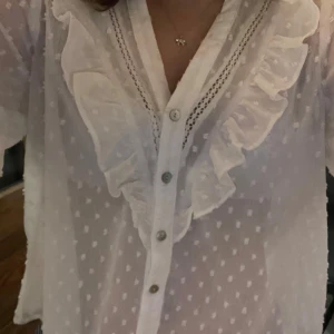 Vit prickig blus med volanger från Zara - Jag säljer min superfina blus med lite volanger från Zara. Har använts ett fåtal gånger, så den är som ny.