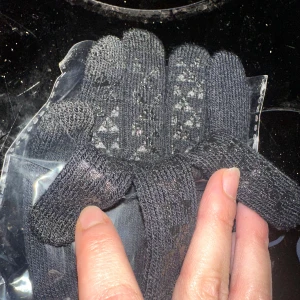 Svarta stickade handskar touchhandskar pekskärmshandskar  - Svarta stickade handskar med diskret mönster på ovansidan. Handskarna är ribbstickade och har en klassisk form med fem fingrar. Perfekta för kyliga dagar och enkla att matcha med din jacka eller hoodie. Touchhandskar onesize 