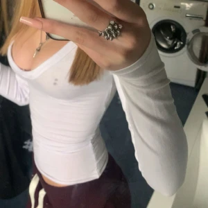Vit långärmad v-ringad topp - Säljer en vit långärmad topp med djup v-ringning och tight passform. Toppen är enkel och stilren, jag har sytt in den så den är extra tight.