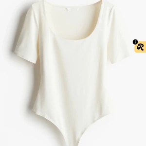 Vit body med kort ärm från H&M - Säljer en stilren vit body från H&M i storlek S. Bodyn har korta ärmar och en djup rundad halsringning som ger en clean look. Materialet är mjukt och stretchigt, perfekt för att matcha med jeans eller kjol. Enkel och snygg design utan mönster eller detaljer.
