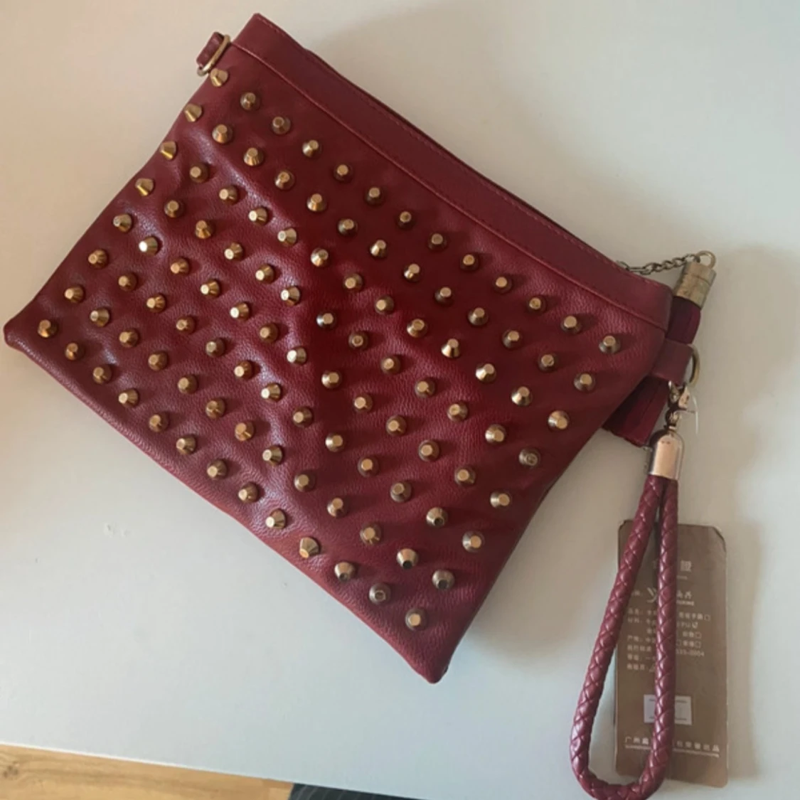 Röd kuvertväska med nitar och tofs