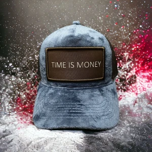 Grå pälsig keps TIME IS MONEY - Unik keps i grått med mjuk pälsig yta och stor brun patch framtill med texten 'TIME IS MONEY' i vitt. Kepsen har böjd skärm och klassisk form, perfekt för dig som vill sticka ut med en cool accessoar.