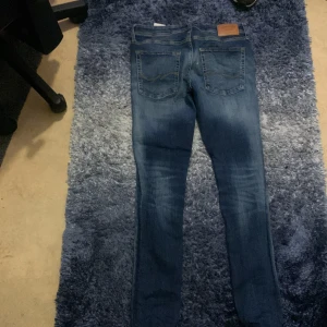 Blå skinny jeans med slitningar - Säljer ett par blå skinny jeans med snygga slitningar och tvättade detaljer på både fram- och baksida. Jeansen har klassisk femficksdesign och smal passform hela vägen ner. Perfekta för dig som gillar en modern och avslappnad stil. Stl 32-24